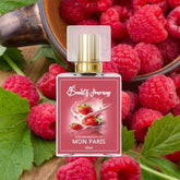 Perfume bottle with berry design, surrounded by fresh raspberries and green leaves