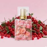 Perfume bottle with gold cap labeled Gucci Flora, floral design, surrounded by red berries on pink background